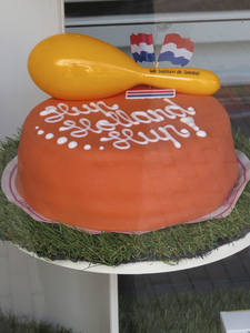 908134 Afbeelding van een oranje chipolatataart met de teksten: 'Hup Holland Hup' en 'We bakken de Samba!', in de ...